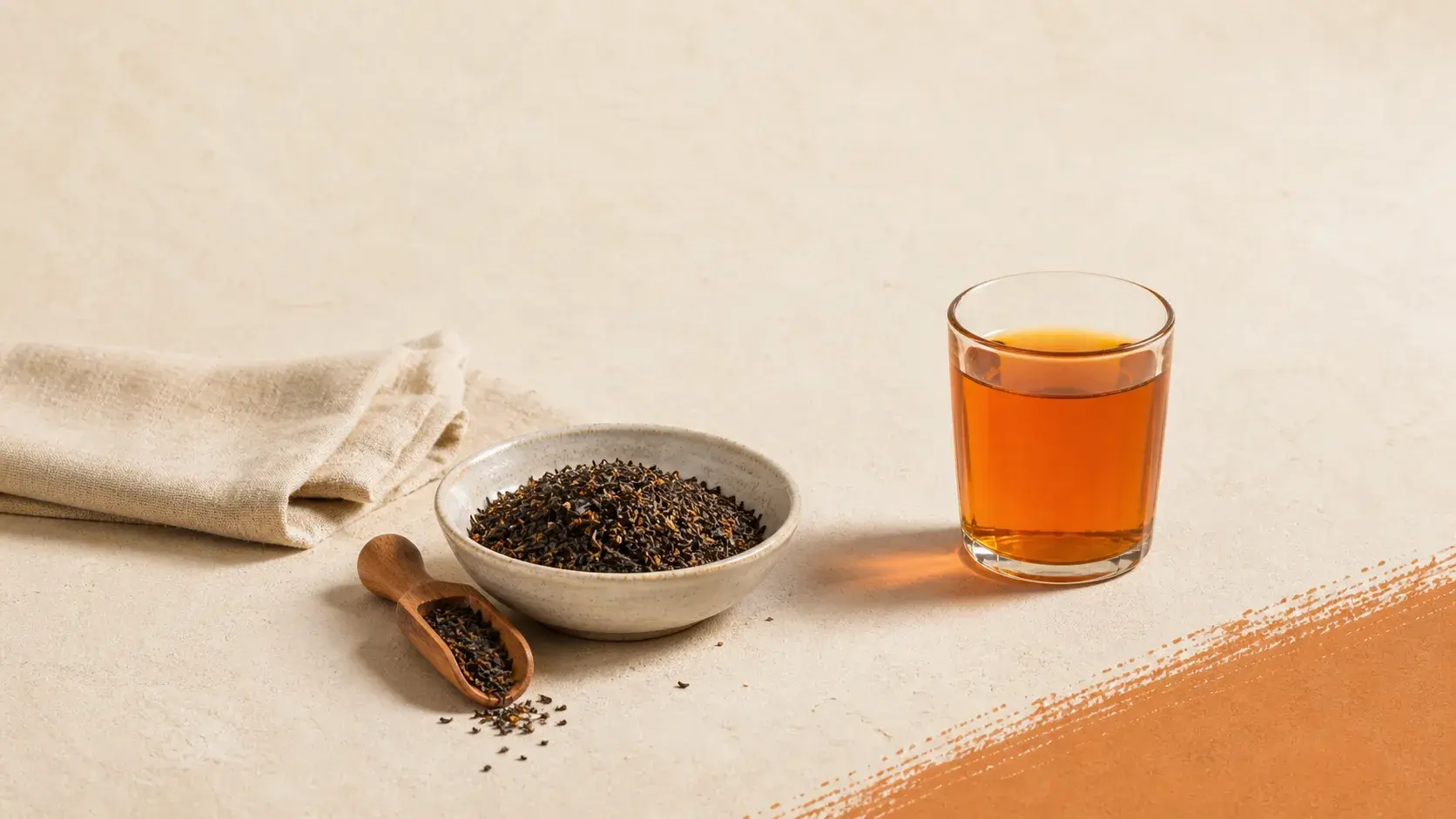 Loose Thai tea leaves beside a brewed glass of tea