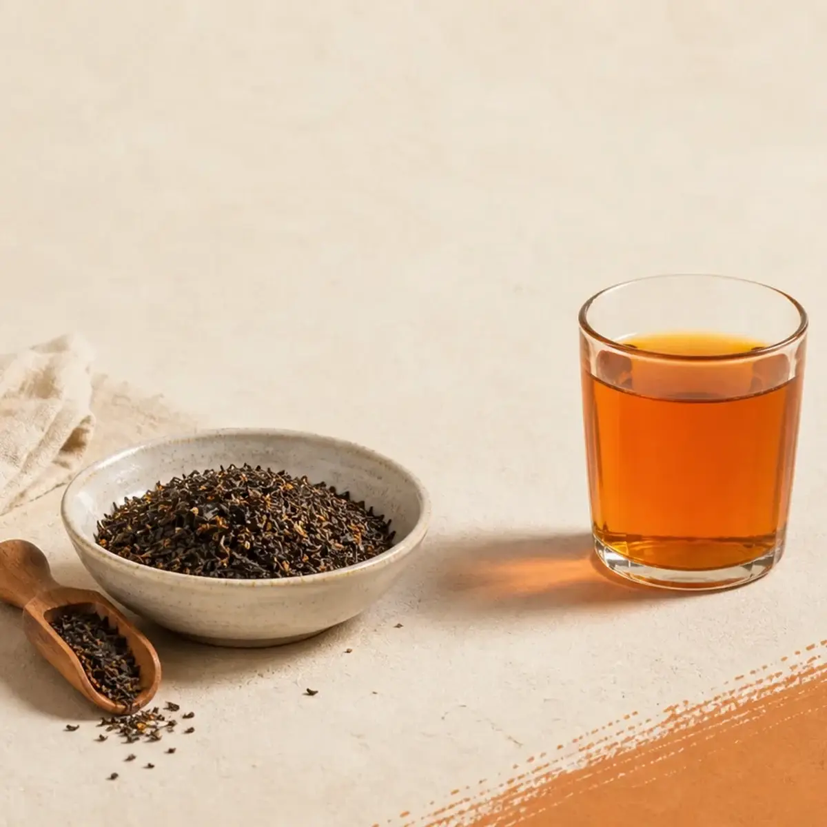 Loose Thai tea leaves beside a brewed glass of tea